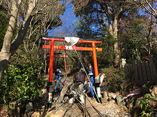 （リニューアル）鳥居を起こしたあと、ロープを固定して柱の穴をコンクリートで埋めるところ　
